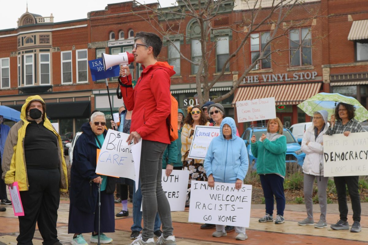 Liz Rodrigues, organizer, speaks before a crowd of protestors on Thursday, May 1, in Central Park, Grinnell.